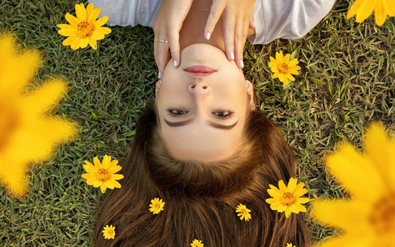 pexels-photo-1821095-1821095 Upside down portrait of a woman lying on grass with yellow flowers in her hair.